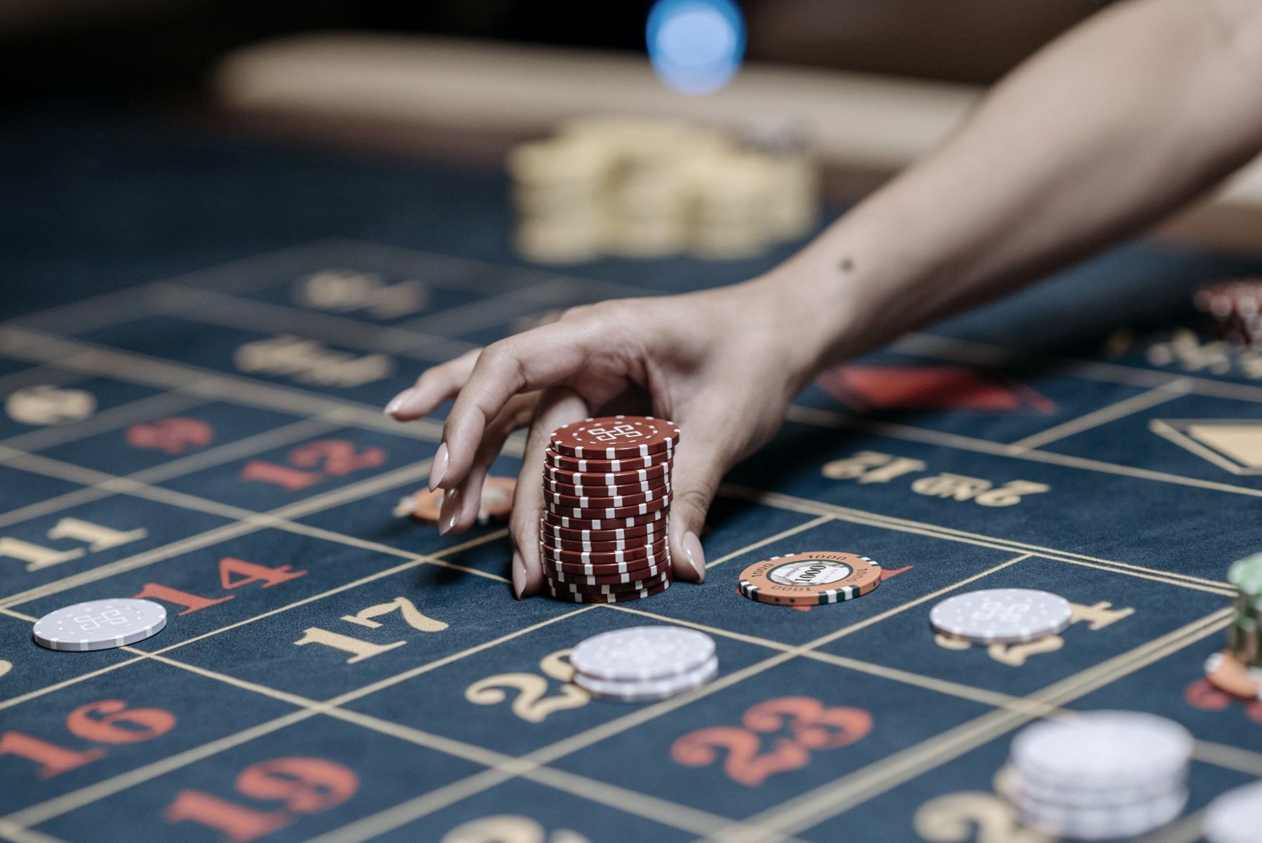 A hand placing casino chips on a roulette table