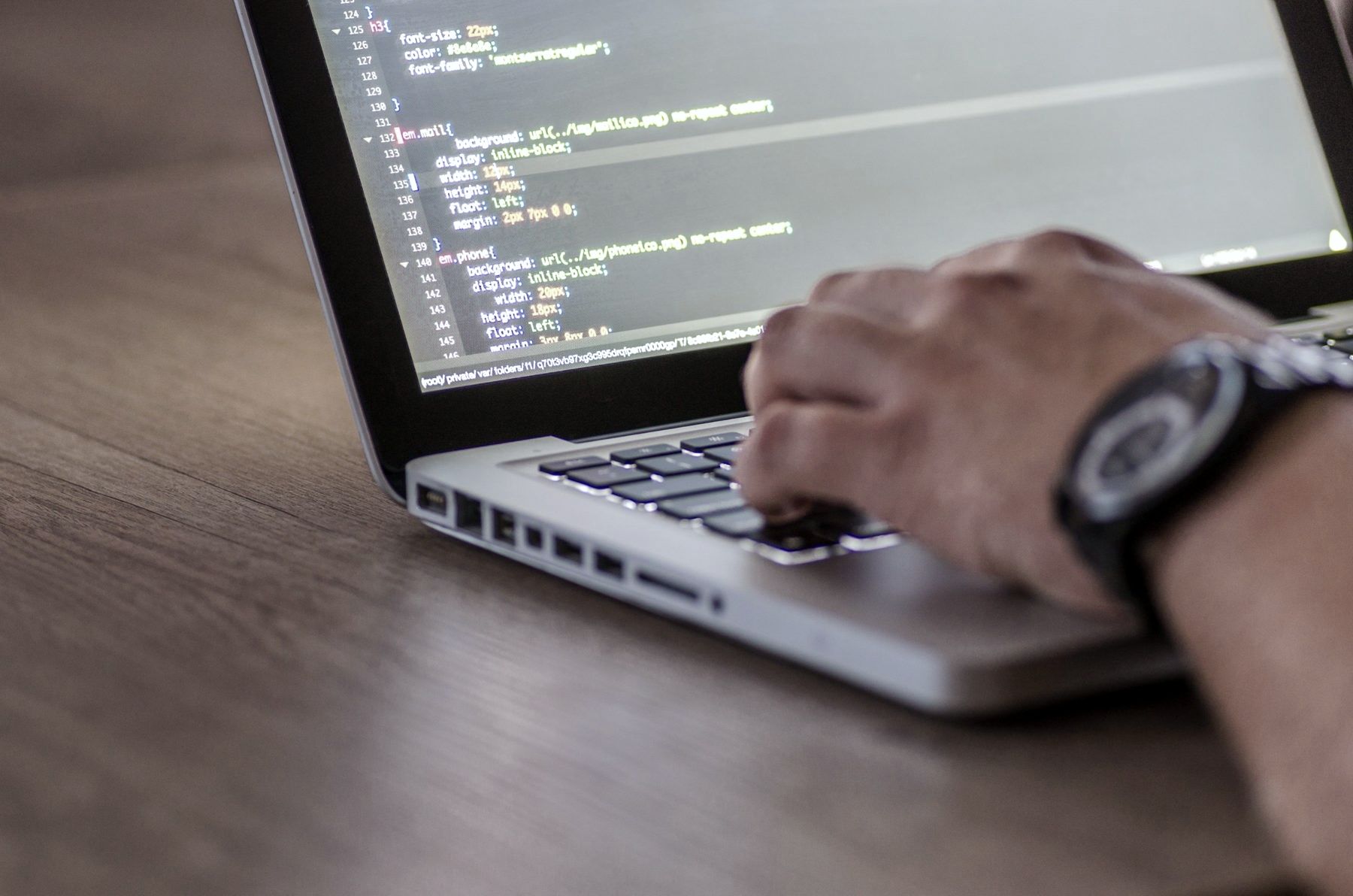 Hands typing on a laptop showing code